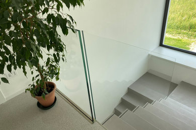 Foto di una scala sospesa moderna con pedata in cemento, nessuna alzata e parapetto in vetro