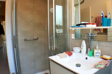 Photo of a medium sized classic shower room bathroom in Nice with flat-panel cabinets, white cabinets, a corner shower, a bidet, grey tiles, ceramic tiles, grey walls, ceramic flooring, a console sink, solid surface worktops, grey floors, a sliding door, white worktops, a single sink and a floating vanity unit.