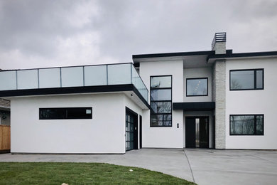 Example of a mid-sized trendy white two-story stucco exterior home design in Vancouver