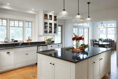 Large cottage u-shaped light wood floor eat-in kitchen photo in Burlington with black backsplash, an island, an undermount sink, shaker cabinets, white cabinets, granite countertops, stone slab backsplash and stainless steel appliances