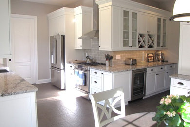 Mid-sized elegant porcelain tile kitchen photo in New York with a farmhouse sink, shaker cabinets, white cabinets, granite countertops, gray backsplash, ceramic backsplash and stainless steel appliances