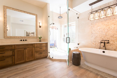 Example of a mid-sized tuscan master beige tile and travertine tile porcelain tile and beige floor freestanding bathtub design in Phoenix with shaker cabinets, medium tone wood cabinets, a one-piece toilet, beige walls, an undermount sink, marble countertops and a hinged shower door