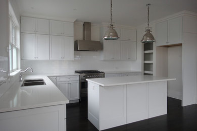 This is an example of a mid-sized transitional l-shaped eat-in kitchen in Melbourne with a double-bowl sink, white cabinets, quartz benchtops, white splashback, ceramic splashback, stainless steel appliances, dark hardwood floors and with island.