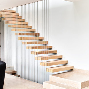 Inspiration for a contemporary wood floating wire cable railing staircase in Wiltshire with open risers.