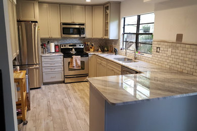 Open concept kitchen - mid-sized traditional l-shaped gray floor and porcelain tile open concept kitchen idea in Tampa with granite countertops, stainless steel appliances, beaded inset cabinets, medium tone wood cabinets, multicolored backsplash, no island, a double-bowl sink and marble backsplash