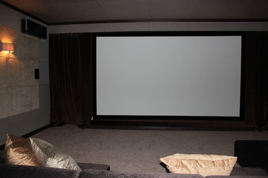 Пример оригинального дизайна: большой изолированный домашний кинотеатр с разноцветными стенами, ковровым покрытием и проектором