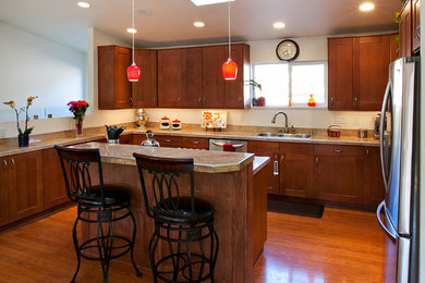 Open concept kitchen - mid-sized transitional l-shaped medium tone wood floor open concept kitchen idea in Other with a drop-in sink, shaker cabinets, medium tone wood cabinets, granite countertops, stainless steel appliances and an island