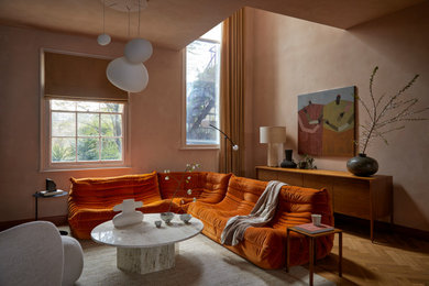 Inspiration for a small contemporary open plan living room in London with orange walls, medium hardwood flooring, a plastered fireplace surround and a wall mounted tv.