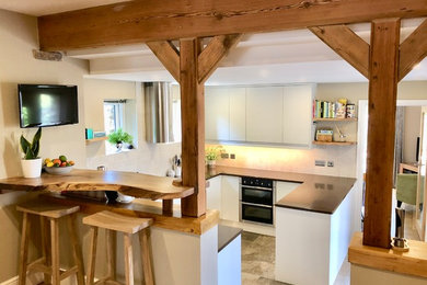 Inspiration for a small country u-shaped kitchen in Other with an integrated sink, flat-panel cabinets, white cabinets, composite countertops, beige splashback, ceramic splashback, stainless steel appliances, ceramic flooring, a breakfast bar, brown floors and brown worktops.