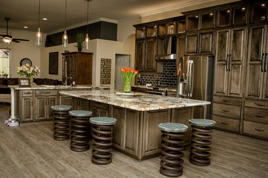 Large elegant l-shaped porcelain tile eat-in kitchen photo in Tampa with an undermount sink, raised-panel cabinets, dark wood cabinets, granite countertops, black backsplash, porcelain backsplash, stainless steel appliances and an island