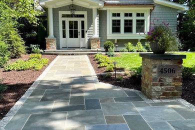 This is an example of a mid-sized traditional full sun front yard stone landscaping in Milwaukee for summer.