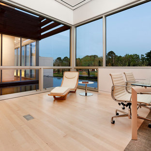 Inspiration for an expansive contemporary study room in Houston with white walls, light hardwood floors, no fireplace and a freestanding desk.