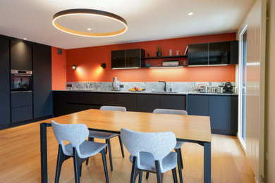 Photo of a large contemporary l-shaped open plan kitchen in Rennes with a double-bowl sink, beaded cabinets, black cabinets, granite worktops, white splashback, granite splashback, integrated appliances, light hardwood flooring, no island and white worktops.