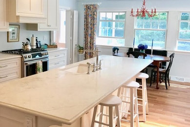 Kitchen - traditional porcelain tile and brown floor kitchen idea in Boston with an undermount sink, shaker cabinets, white cabinets, quartz countertops, stainless steel appliances, an island and white countertops