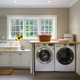 ニューヨークの中サイズのカントリー風おしゃれな家事室 (シェーカースタイル扉のキャビネット、白いキャビネット、大理石カウンター、セラミックタイルの床、左右配置の洗濯機・乾燥機、ベージュのキッチンカウンター、ドロップインシンク、グレーの壁) の写真