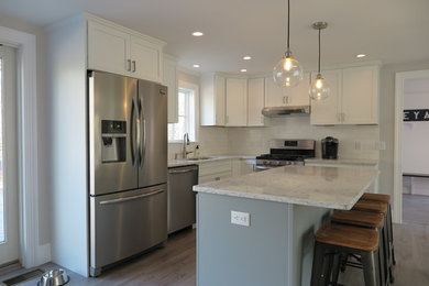 Inspiration for a mid-sized contemporary l-shaped laminate floor and brown floor eat-in kitchen remodel in Boston with an undermount sink, shaker cabinets, white cabinets, quartz countertops, multicolored backsplash, ceramic backsplash, stainless steel appliances and an island