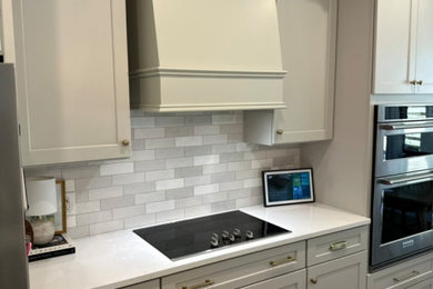 Mid-sized transitional light wood floor and multicolored floor kitchen photo in Tampa with an undermount sink, shaker cabinets, gray cabinets, quartz countertops, gray backsplash, subway tile backsplash, stainless steel appliances, an island and white countertops