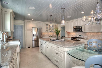 Design ideas for a large transitional u-shaped eat-in kitchen in Tampa with a farmhouse sink, raised-panel cabinets, white cabinets, granite benchtops, beige splashback, stone tile splashback, stainless steel appliances, porcelain floors and with island.