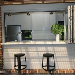 Idéer för ett stort modernt kök, med en undermonterad diskho, släta luckor, vita skåp, bänkskiva i kvarts, brunt stänkskydd, glaspanel som stänkskydd, rostfria vitvaror och skiffergolv