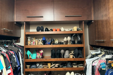 Example of a small trendy women's walk-in closet design in Other with flat-panel cabinets and dark wood cabinets