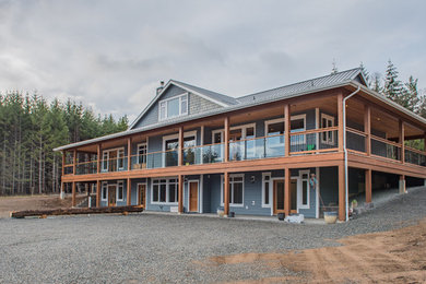 Example of a large cottage blue three-story wood exterior home design in Vancouver with a metal roof