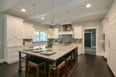 Inspiration for a large transitional u-shaped dark wood floor and brown floor kitchen remodel in Chicago with an island, an undermount sink, recessed-panel cabinets, white cabinets, granite countertops, gray backsplash, subway tile backsplash and stainless steel appliances