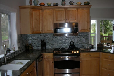 Example of a light wood floor kitchen design in Seattle with a drop-in sink, flat-panel cabinets, light wood cabinets, marble countertops, gray backsplash, glass tile backsplash and stainless steel appliances