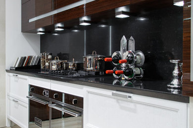 This is an example of a large transitional galley eat-in kitchen in Moscow with an undermount sink, flat-panel cabinets, white cabinets, quartz benchtops, black splashback, marble splashback, black appliances, laminate floors, with island and beige floor.