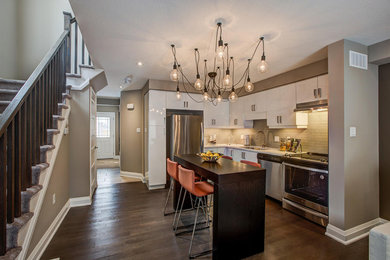 Example of a mid-sized trendy l-shaped medium tone wood floor and brown floor kitchen design in Toronto with an undermount sink, flat-panel cabinets, white cabinets, wood countertops, brown backsplash, matchstick tile backsplash, stainless steel appliances and an island