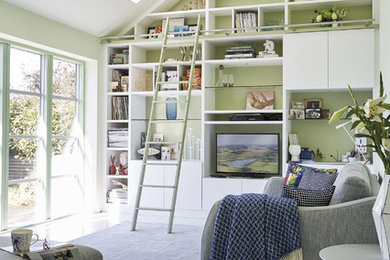 This is an example of a medium sized contemporary open plan games room in Manchester with a reading nook, green walls, light hardwood flooring, a built-in media unit and white floors.