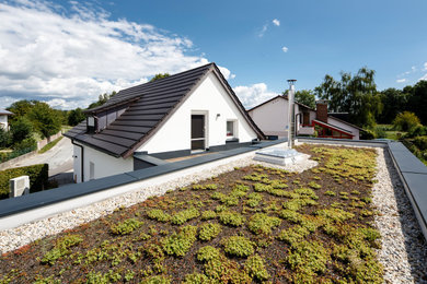 ミュンヘンにある小さなモダンスタイルのおしゃれな家の外観 (漆喰サイディング、緑化屋根) の写真