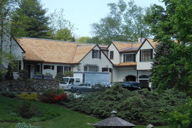 Photo of a large traditional two-storey stucco white house exterior in Boston with a gable roof and a shingle roof.