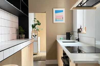 This is an example of a scandinavian kitchen in Other with a single-bowl sink, light wood cabinets, quartzite benchtops, white splashback, engineered quartz splashback, black appliances and white benchtop.