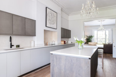 Inspiration for a large contemporary kitchen/diner in Gloucestershire with flat-panel cabinets, grey cabinets, quartz worktops, white splashback, an island and white worktops.