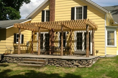 Example of a large transitional backyard stone patio design in New York with a pergola