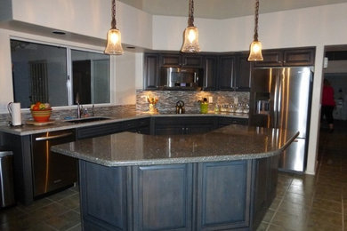 Mid-sized trendy terra-cotta tile kitchen photo in Phoenix with dark wood cabinets, granite countertops, stainless steel appliances and an island