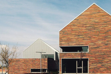 Diseño de fachada multicolor moderna extra grande de tres plantas con revestimiento de ladrillo, tejado a dos aguas y tejado de metal