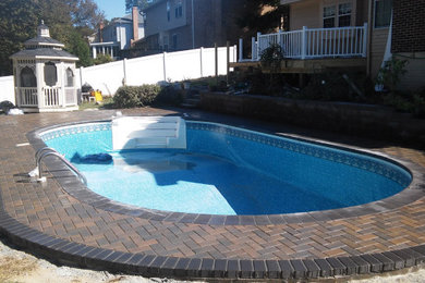 Mid-sized backyard concrete paver and round natural pool landscaping photo in DC Metro