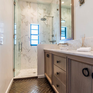Aménagement d'une petite salle de bain classique avec un placard avec porte à panneau encastré, des portes de placard en bois brun, un carrelage blanc, des dalles de pierre, un mur blanc, un sol en brique, un lavabo encastré, un plan de toilette en marbre, un sol marron, une cabine de douche à porte battante et un plan de toilette blanc.