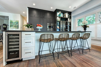 Eat-in kitchen - mid-sized transitional galley medium tone wood floor and brown floor eat-in kitchen idea in Charleston with a farmhouse sink, shaker cabinets, gray cabinets, quartz countertops, stainless steel appliances, an island and gray countertops