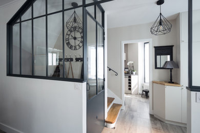 Mid-sized contemporary mudroom in Paris with grey walls, light hardwood floors, a black front door and grey floor.