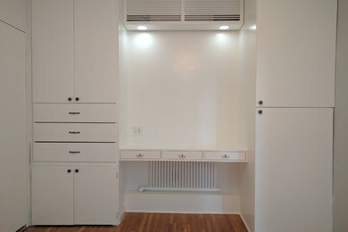Utility room - mid-sized traditional medium tone wood floor utility room idea in New York with white walls, flat-panel cabinets and white cabinets