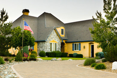Inspiration for a large timeless yellow two-story concrete exterior home remodel in Other with a gambrel roof