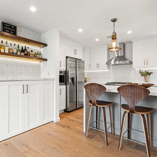 ロサンゼルスの中サイズのトランジショナルスタイルのおしゃれなホームバー (シェーカースタイル扉のキャビネット、白いキャビネット、クオーツストーンカウンター、白いキッチンパネル、淡色無垢フローリング、茶色い床、セメントタイルのキッチンパネル、白いキッチンカウンター) の写真