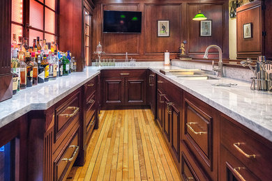 Seated home bar - large traditional u-shaped medium tone wood floor seated home bar idea in Denver with a drop-in sink, raised-panel cabinets, medium tone wood cabinets, granite countertops and wood backsplash