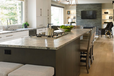 Large trendy u-shaped light wood floor and beige floor open concept kitchen photo in Calgary with an undermount sink, flat-panel cabinets, granite countertops, gray backsplash, subway tile backsplash, stainless steel appliances, an island and white cabinets
