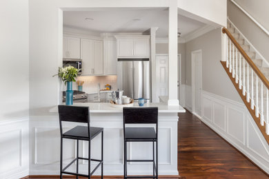 Example of a small transitional u-shaped medium tone wood floor and brown floor open concept kitchen design in DC Metro with an undermount sink, shaker cabinets, gray cabinets, quartz countertops, white backsplash, ceramic backsplash, stainless steel appliances, a peninsula and white countertops