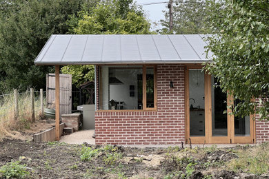 Inspiration for a classic bungalow brick and rear house exterior in Wiltshire with a metal roof and a black roof.