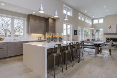 Photo of a large modern kitchen in San Francisco with an undermount sink, flat-panel cabinets, medium wood cabinets, quartz benchtops, stainless steel appliances, light hardwood floors, with island and brown floor.