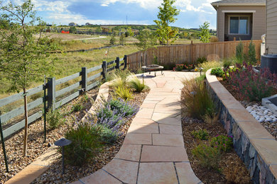Mid-sized backyard full sun xeriscape in Denver with a retaining wall and natural stone pavers for summer.